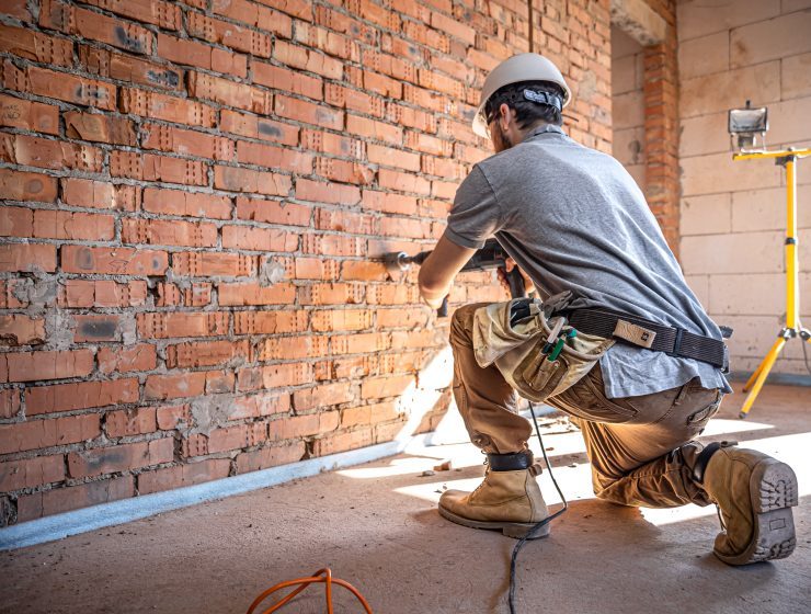 A builder works with a drill at a construction site.